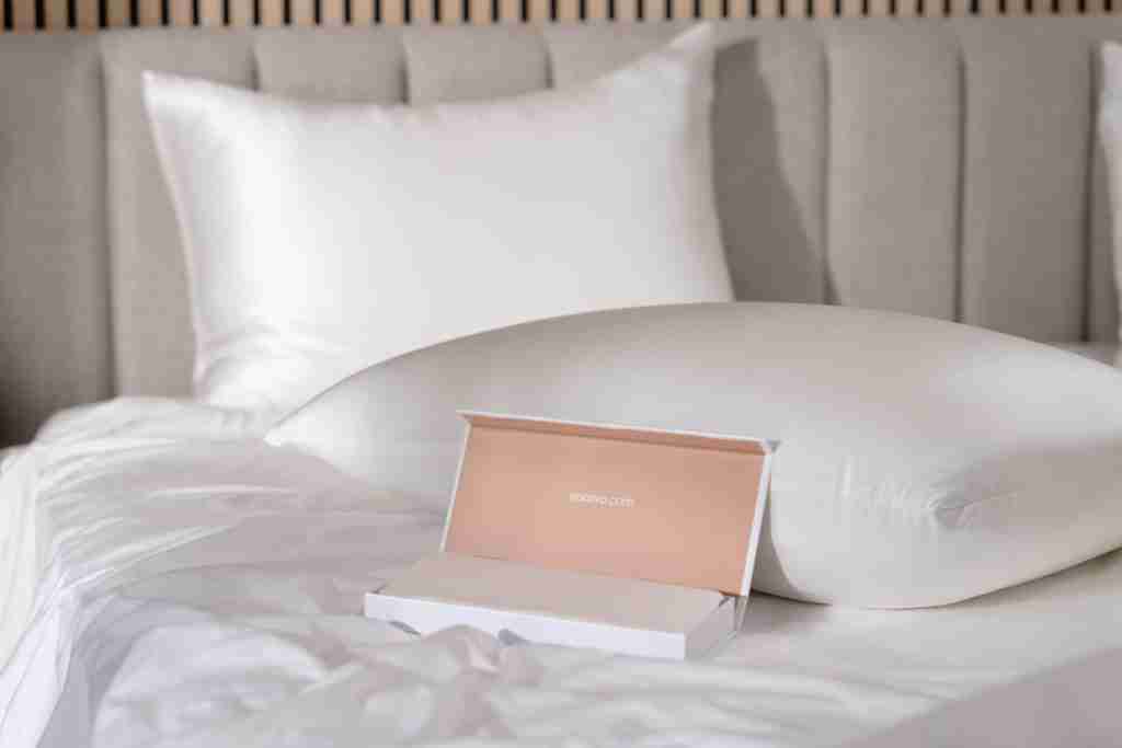 Saatva silk pillowcase, silk Eyemask, and gift box on white organic bedding